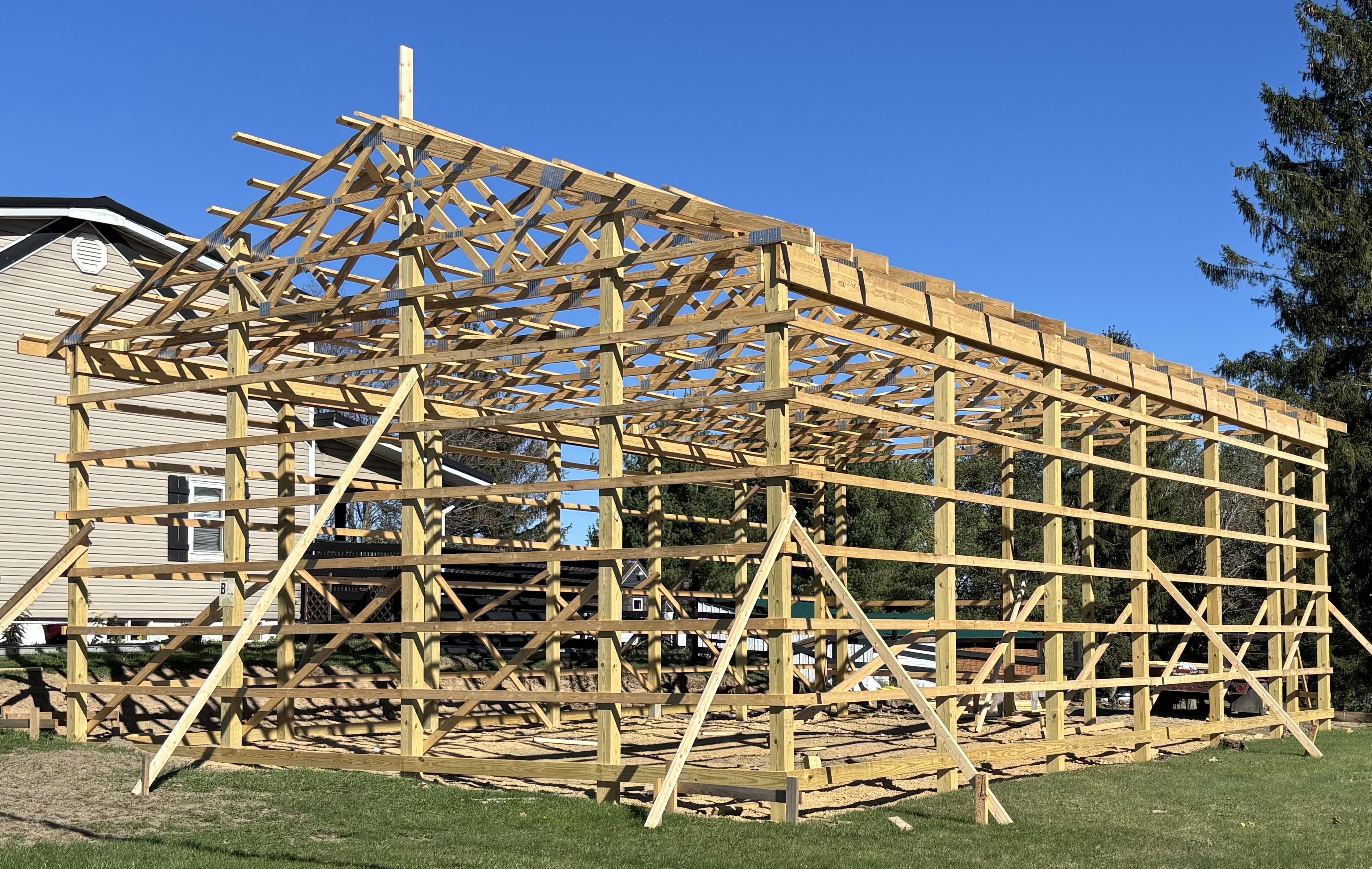 Pole barn in construction with posts, beams, trusses, girts and prulins